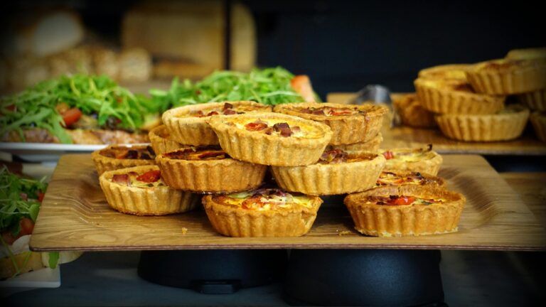 A tempting display of homemade quiches topped with fresh ingredients on a wooden tray.